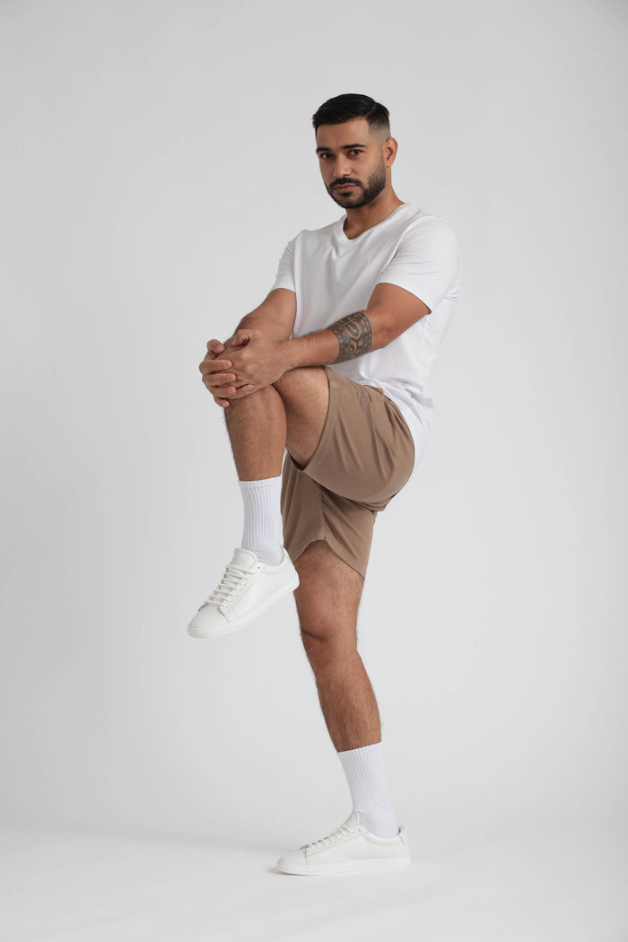 Man wearing light khaki slim fit shorts with white t-shirt and white sneakers.