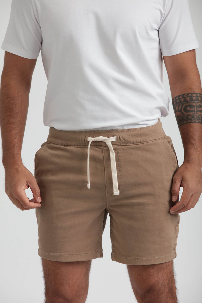 Man wearing white t-shirt and tan shorts with drawstring waist and side pockets.