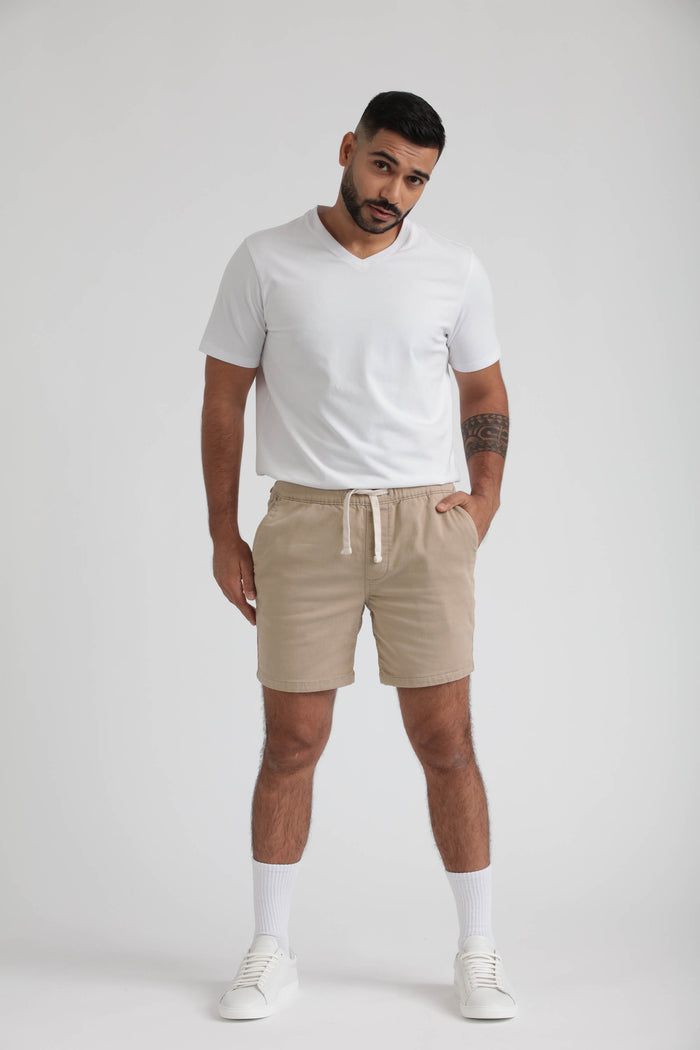 Beige slim fit shorts with drawstring waist, paired with white t-shirt and white sneakers.