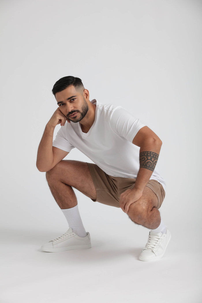 Man wearing dark khaki slim fit shorts with white t-shirt, white socks, and white sneakers.