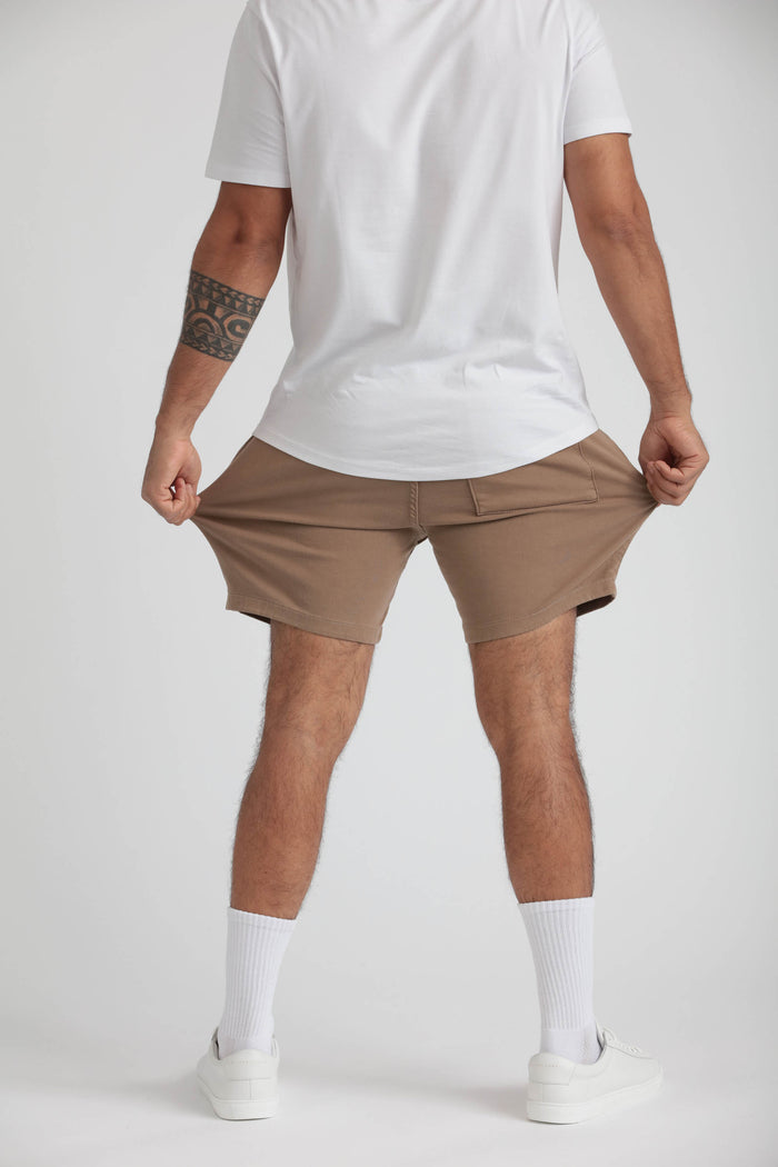 Slim fit khaki shorts with front pockets on male model wearing white t-shirt and white socks.