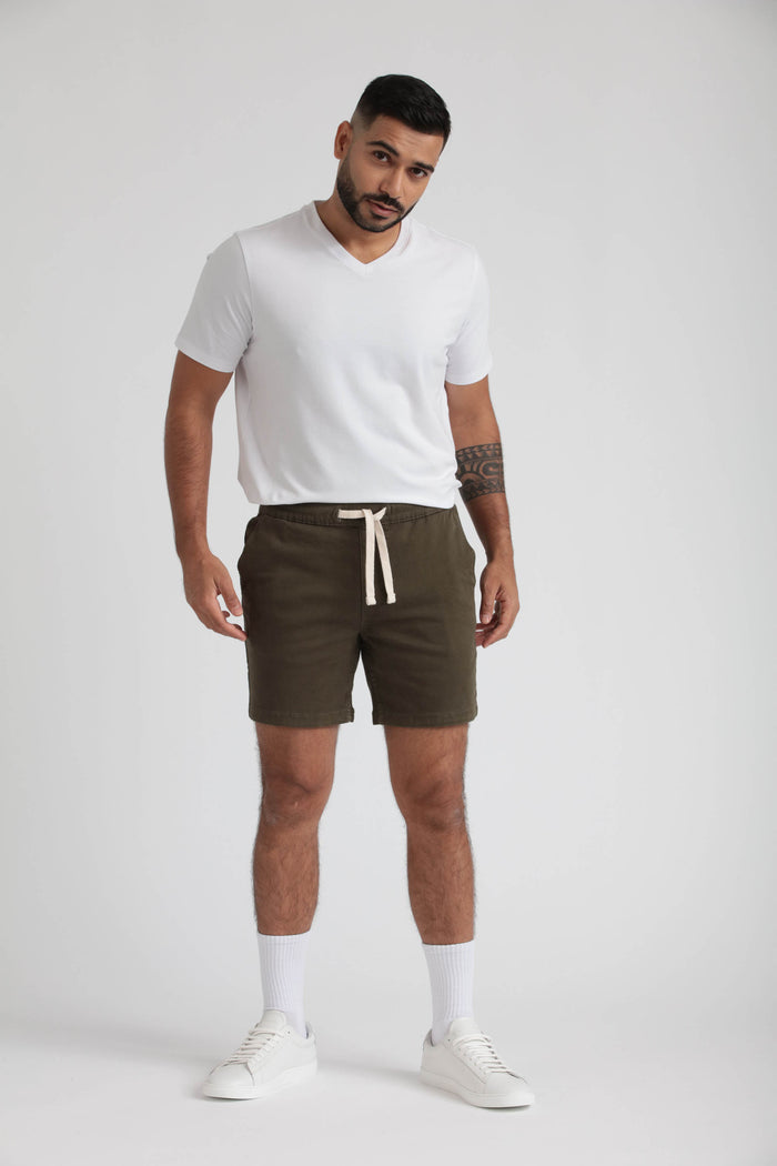 Man wearing olive green slim fit shorts with drawstring waist and white V-neck t-shirt.
