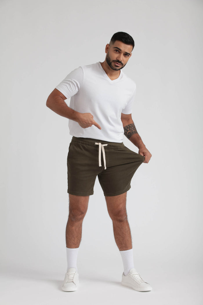 Man wearing white t-shirt and olive green shorts with drawstring waistband and white socks.
