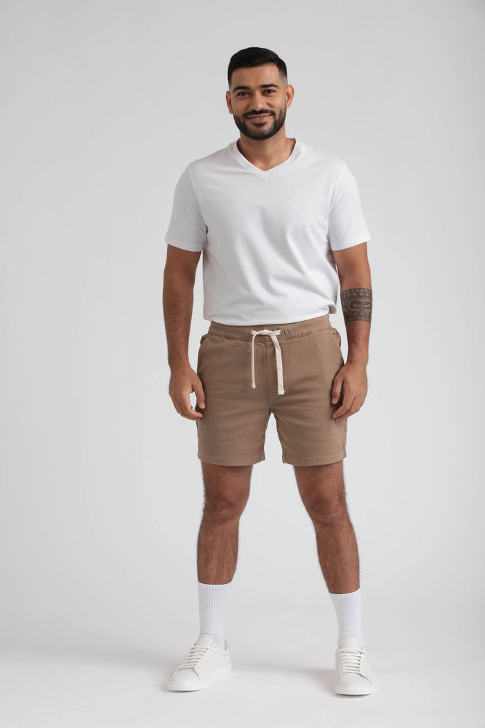 Man wearing dark khaki slim fit shorts with drawstring waist and white v-neck t-shirt.