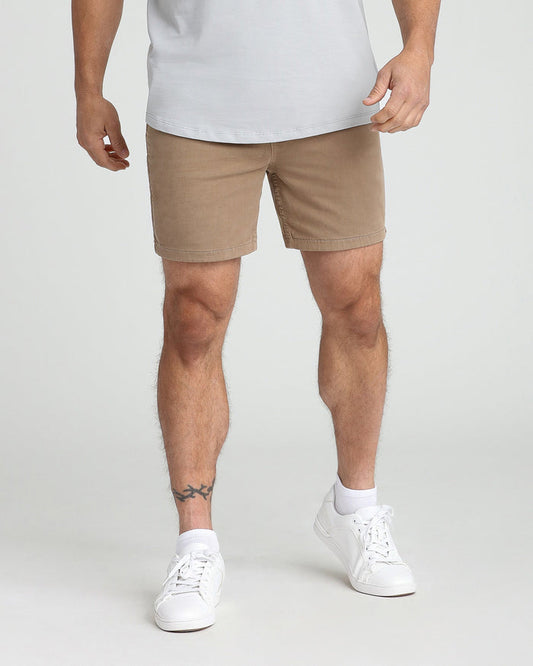 Dark khaki slim-fit shorts on a man wearing a white t-shirt and white sneakers.