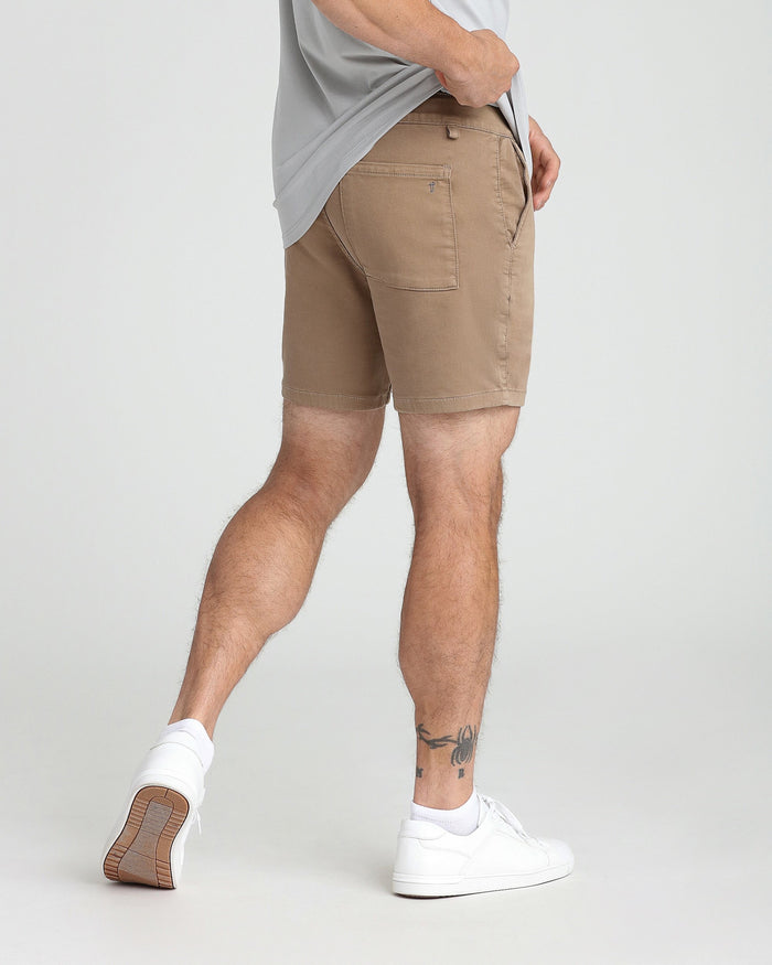 Dark khaki slim fit shorts with back pocket detail, worn with gray t-shirt and white sneakers.
