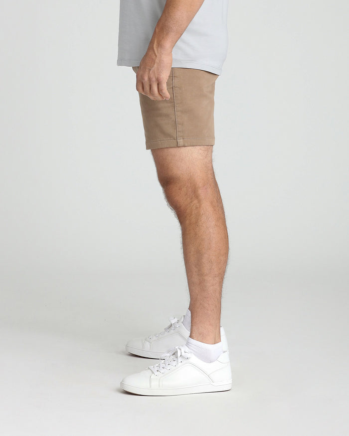 Men's dark khaki slim fit shorts with white sneakers and white socks on model.