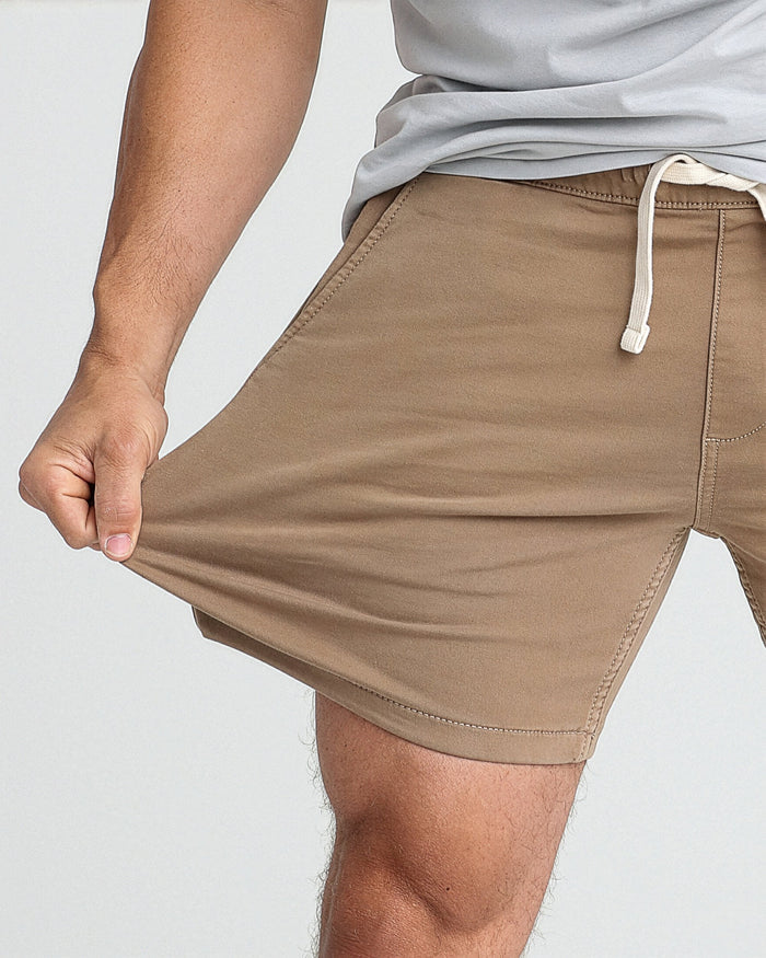 Dark khaki slim fit shorts with white drawstring, worn with light gray t-shirt.