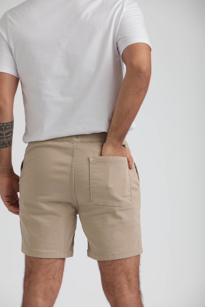 Man wearing light khaki slim fit shorts with back pocket, paired with white t-shirt.