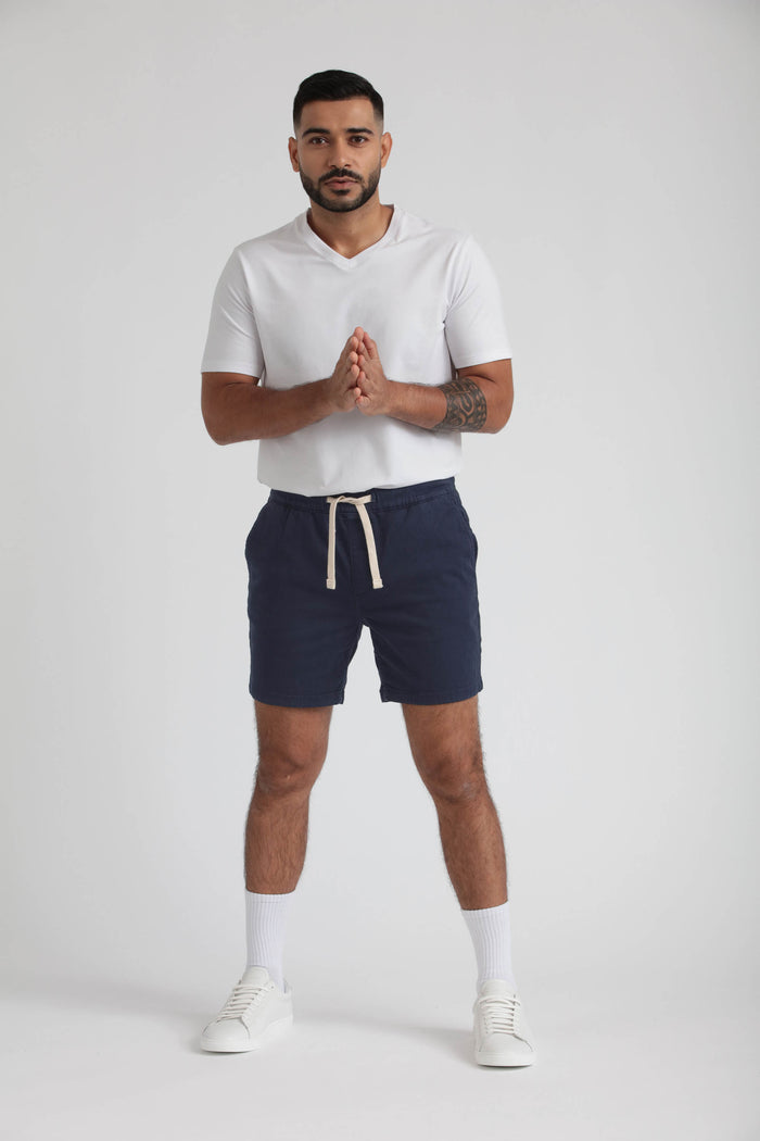 Man wearing white v-neck t-shirt and navy slim fit shorts with drawstring waist.