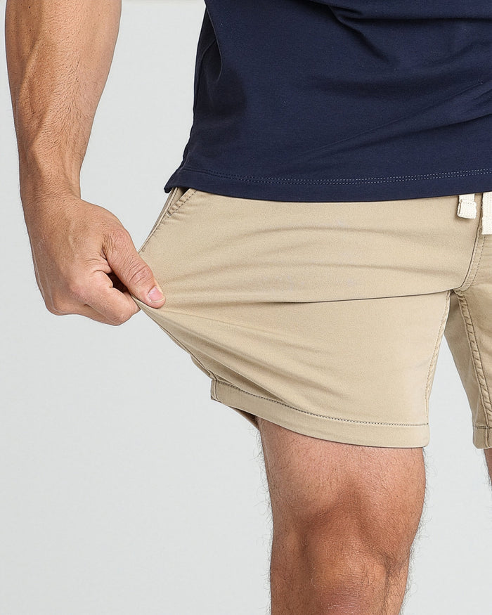 Light khaki slim-fit shorts on model with navy shirt, showing fit at waist and thigh.
