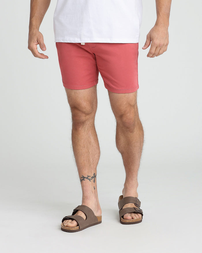 Man wearing nantucket red slim fit shorts with white shirt and brown sandals.
