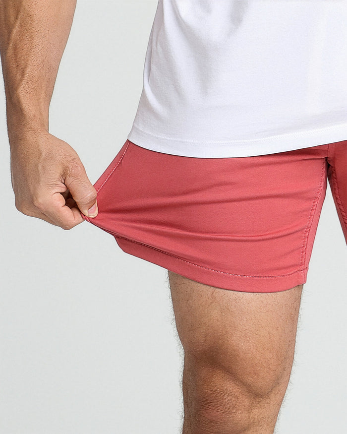 Man wearing red slim-fit shorts with white t-shirt, showing fabric stretch and fit at waistband.
