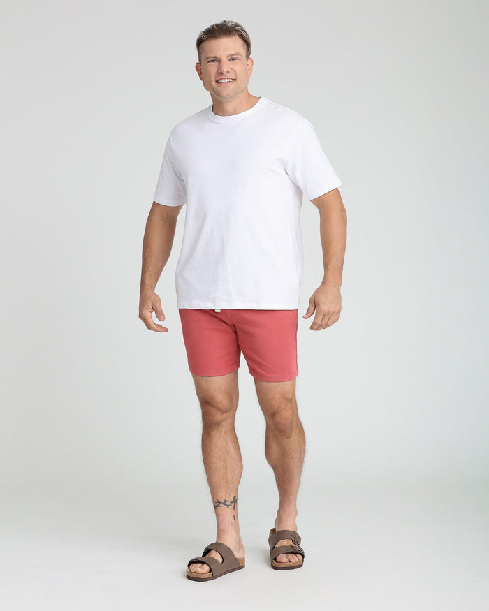Man wearing white t-shirt and nantucket red slim fit shorts with brown sandals.
