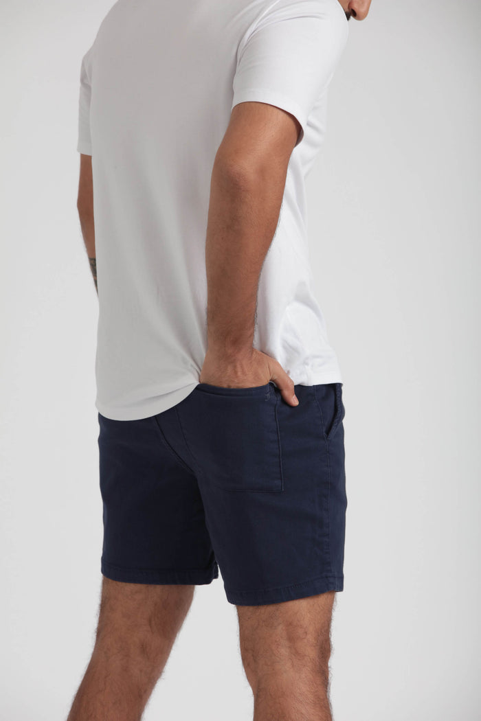 Man wearing white t-shirt and navy slim fit shorts with front pocket detail.
