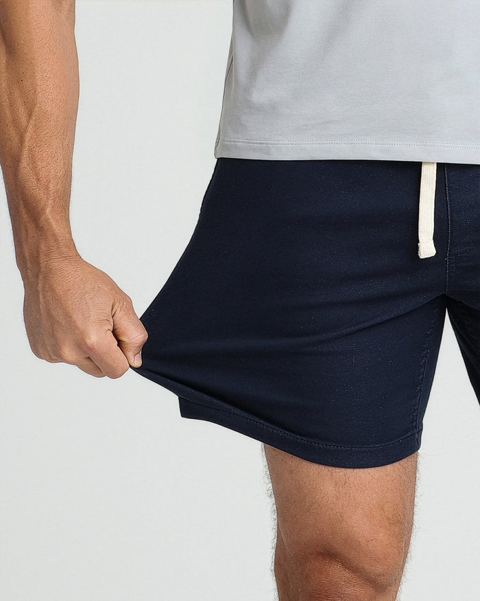 Navy slim fit shorts with drawstring waistband, shown on model wearing gray t-shirt.