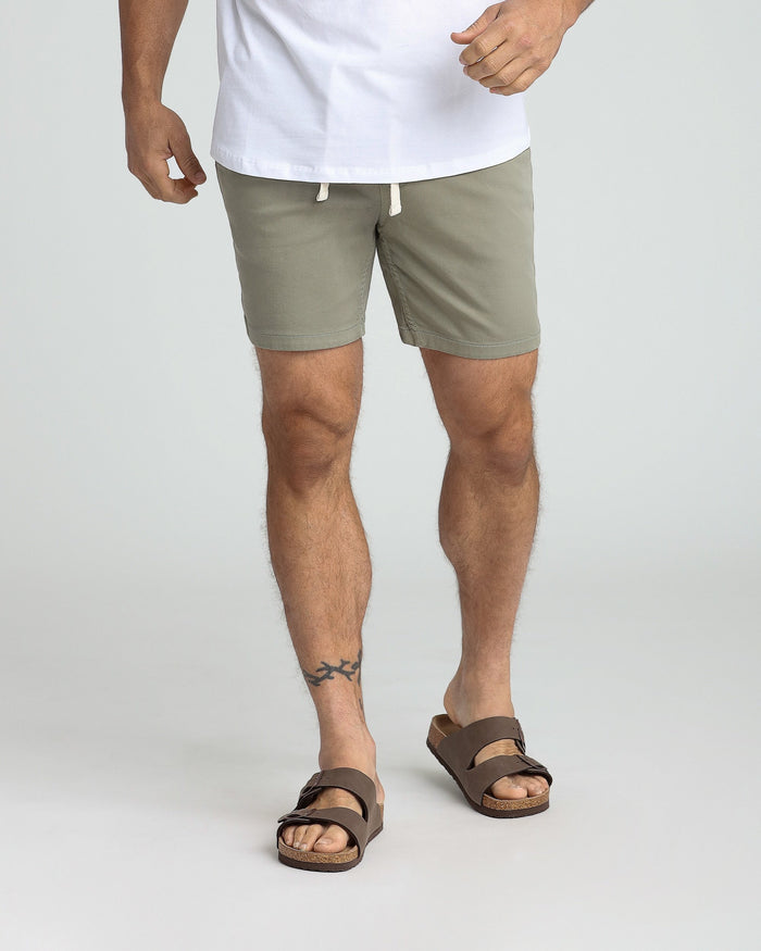Man wearing sage green slim fit shorts with white drawstring and brown sandals.
