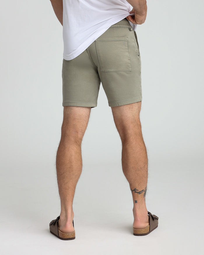 Man wearing sage green slim fit shorts with white t-shirt, shown from behind.