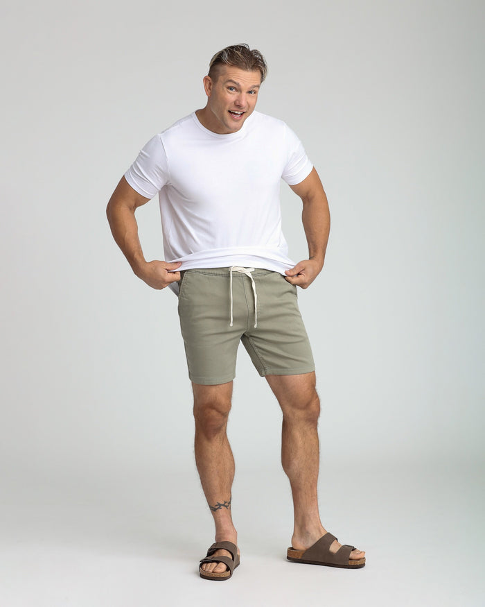 Sage green slim fit shorts with drawstring waist, shown on male model with white t-shirt and sandals.