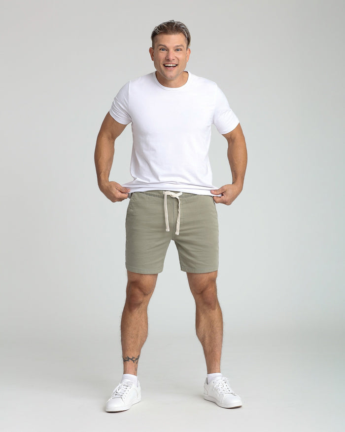 Man wearing white t-shirt and sage green slim fit shorts with drawstring waist.