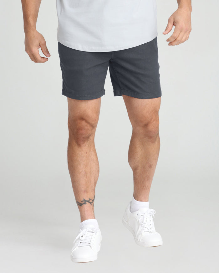 Man wearing slate gray slim fit shorts with white sneakers and white t-shirt.