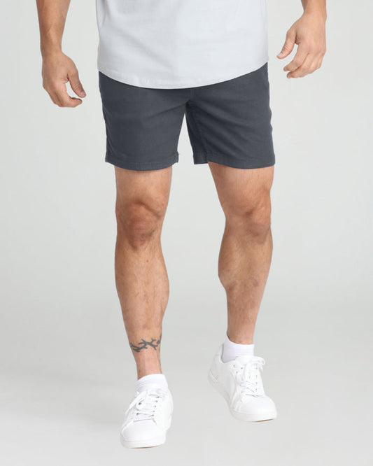 Man wearing slate gray slim fit shorts with white sneakers and white t-shirt.