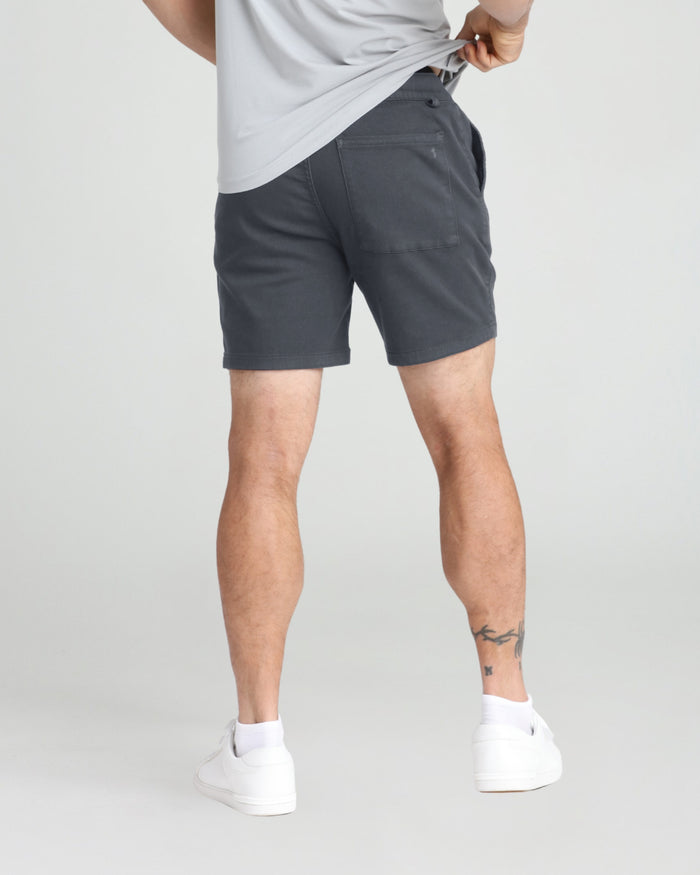 Slate gray slim fit shorts with back pockets worn with white t-shirt and white sneakers.