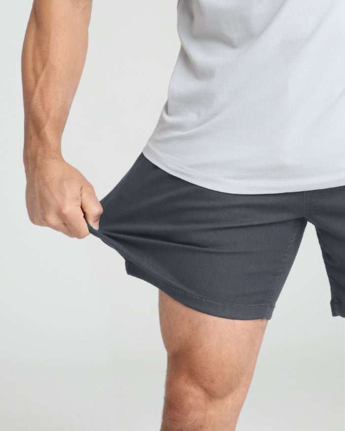 Slate-colored slim fit shorts on a man wearing a white t-shirt, showing the fit and length.