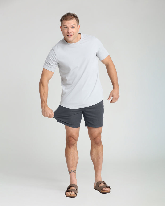 Man wearing slate gray slim fit shorts with white t-shirt and sandals.