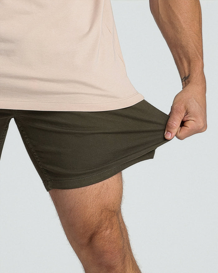 Soldier olive slim fit shorts on model wearing cream t-shirt, shown from waist down.