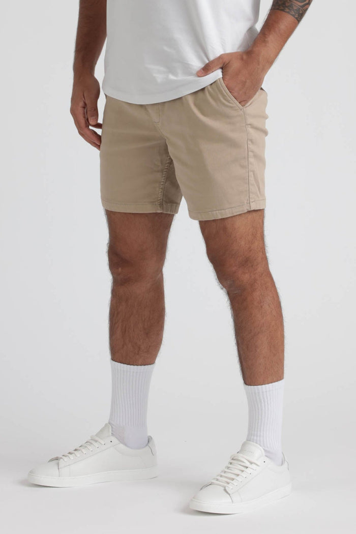 Beige slim fit shorts with front pockets worn with white t-shirt, white socks, and white sneakers.