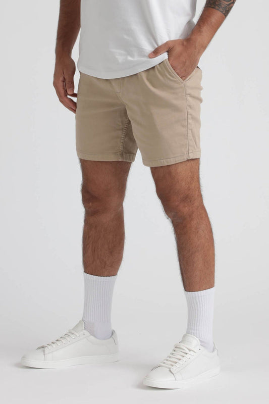 Beige slim fit shorts with front pockets worn with white t-shirt, white socks, and white sneakers.