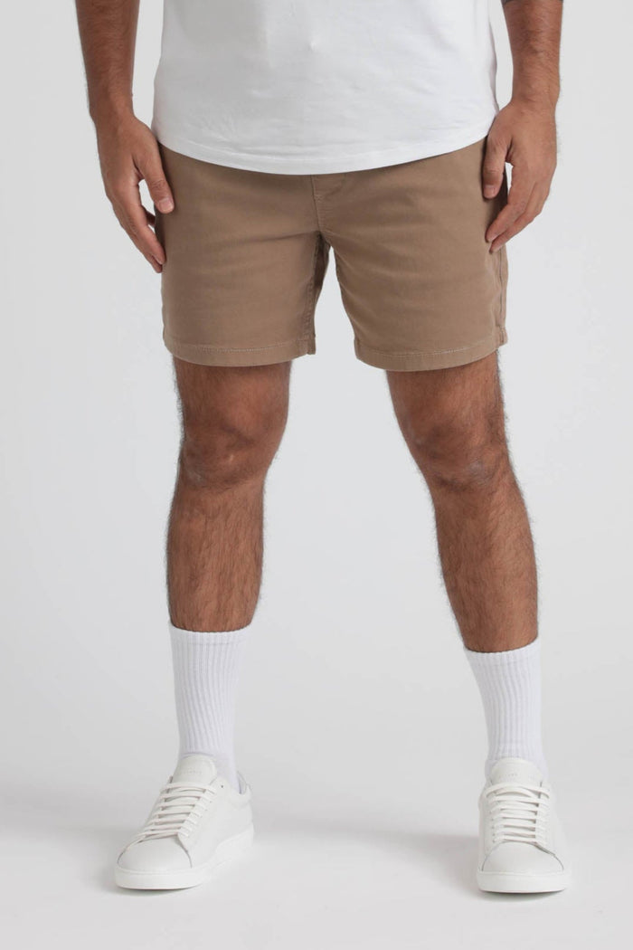 Khaki slim fit shorts on model wearing white socks and white sneakers.