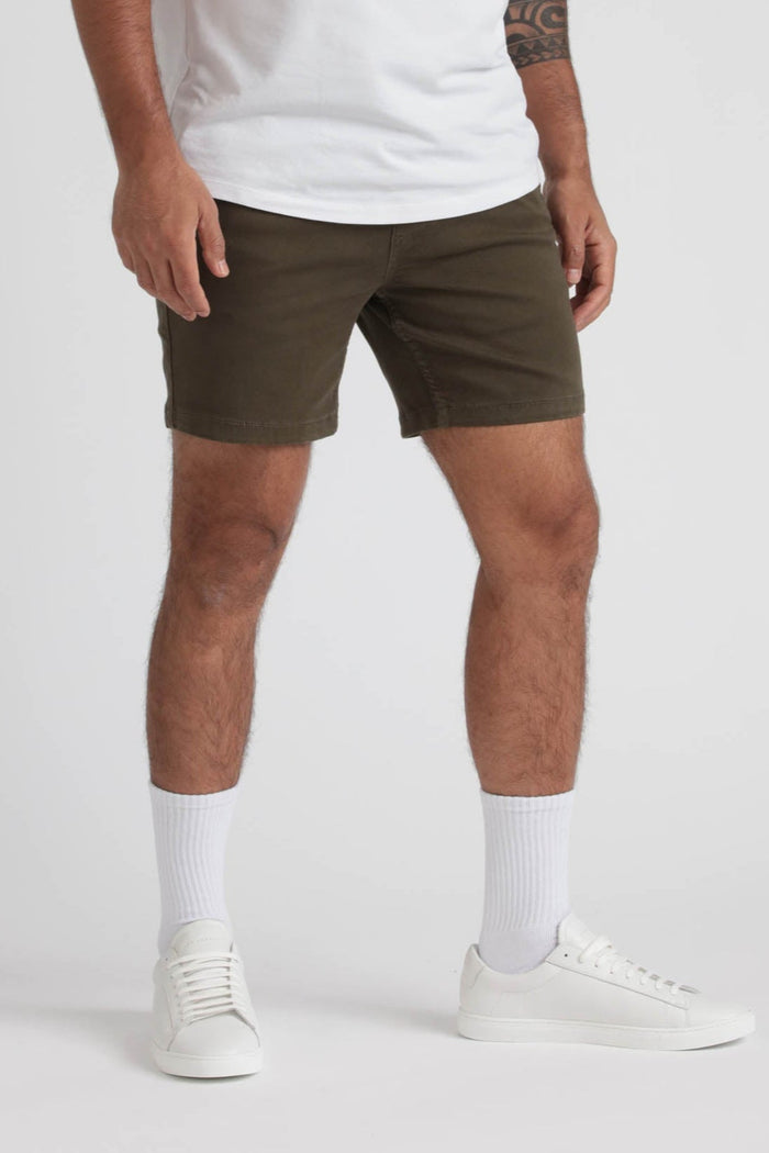 Man wearing olive green slim fit shorts with white t-shirt, white socks, and white sneakers.