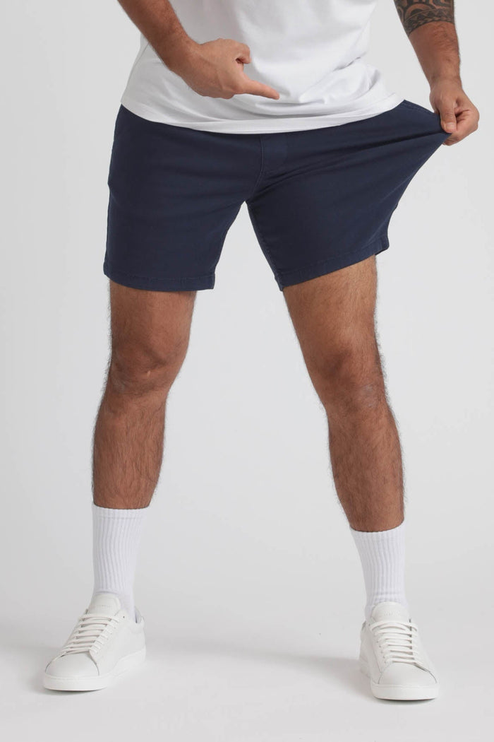 Man wearing navy slim fit shorts with white t-shirt, white socks, and white sneakers.