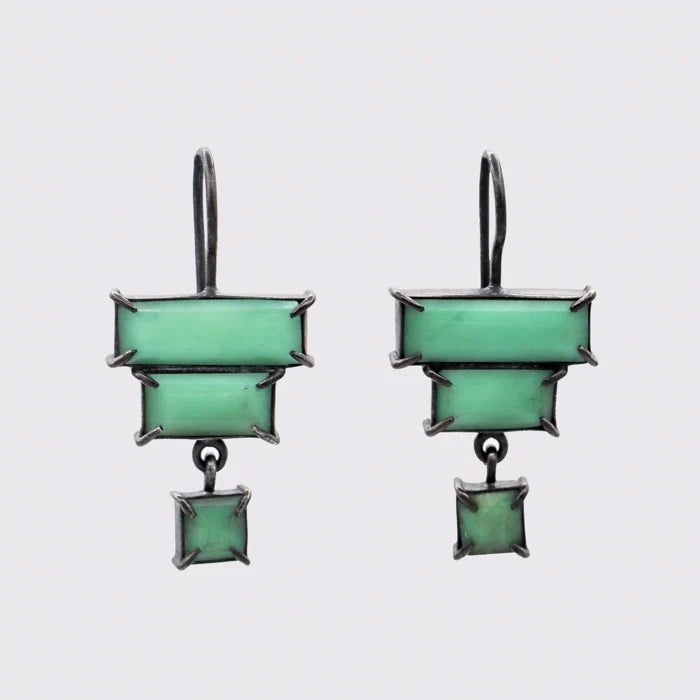 Pair of green square earrings with silver accents on a light gray background