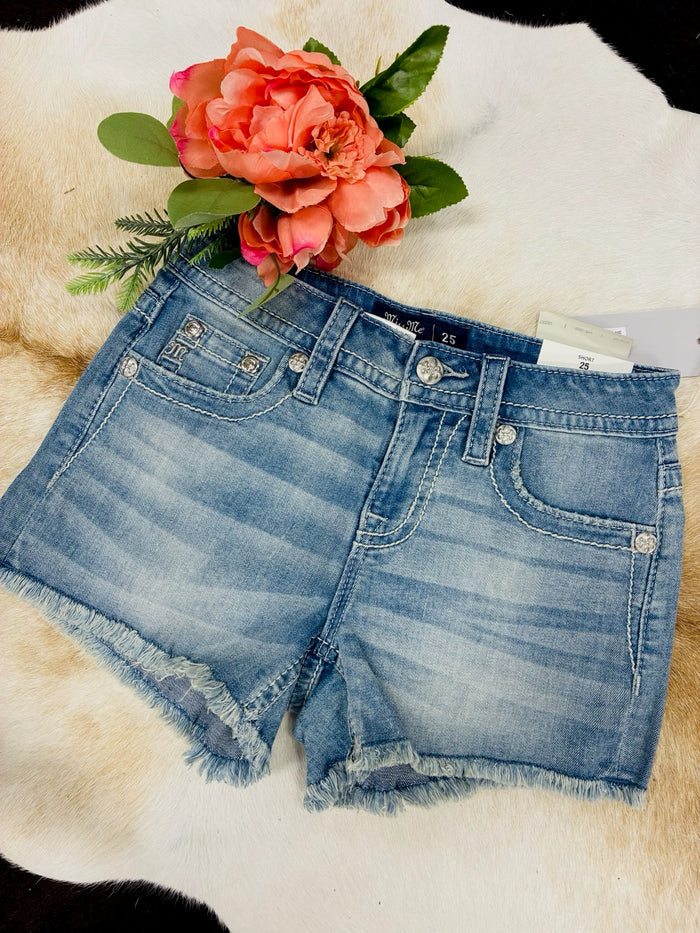 Blue denim shorts with a floral arrangement on a textured surface