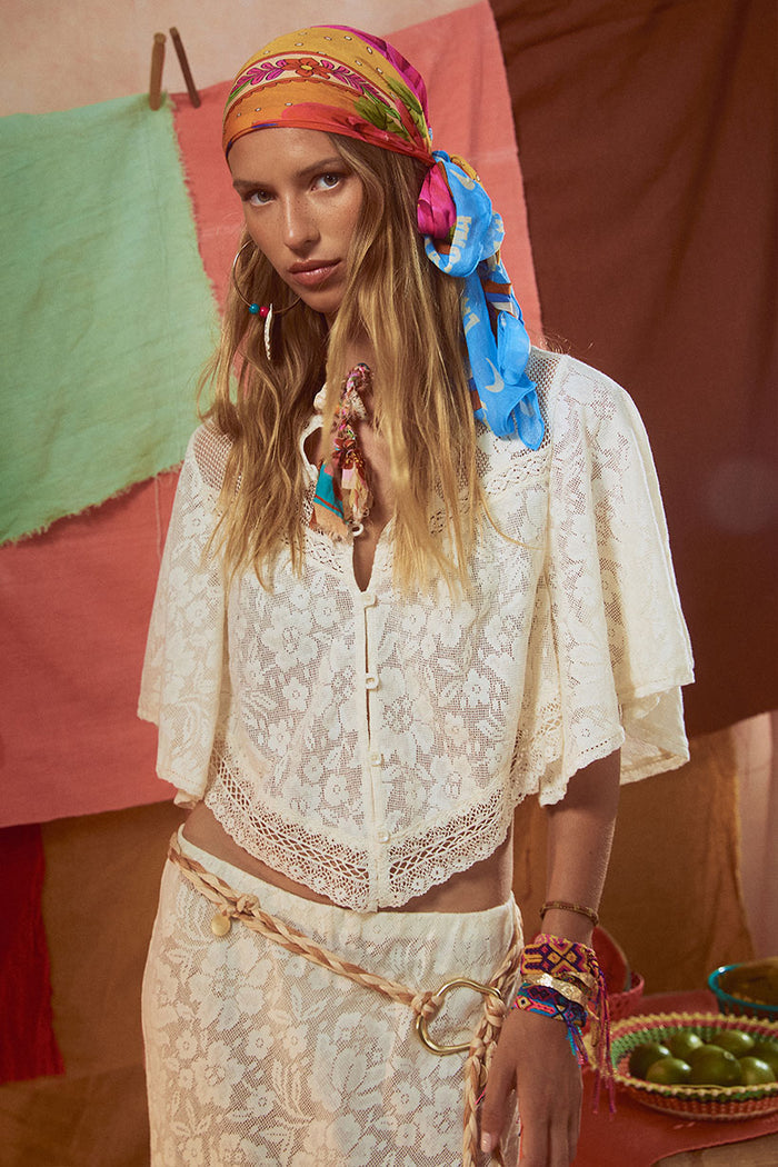 Front view of vintage cream lace crop top with corozo buttons, flutter sleeves, and contrast lace hem detail