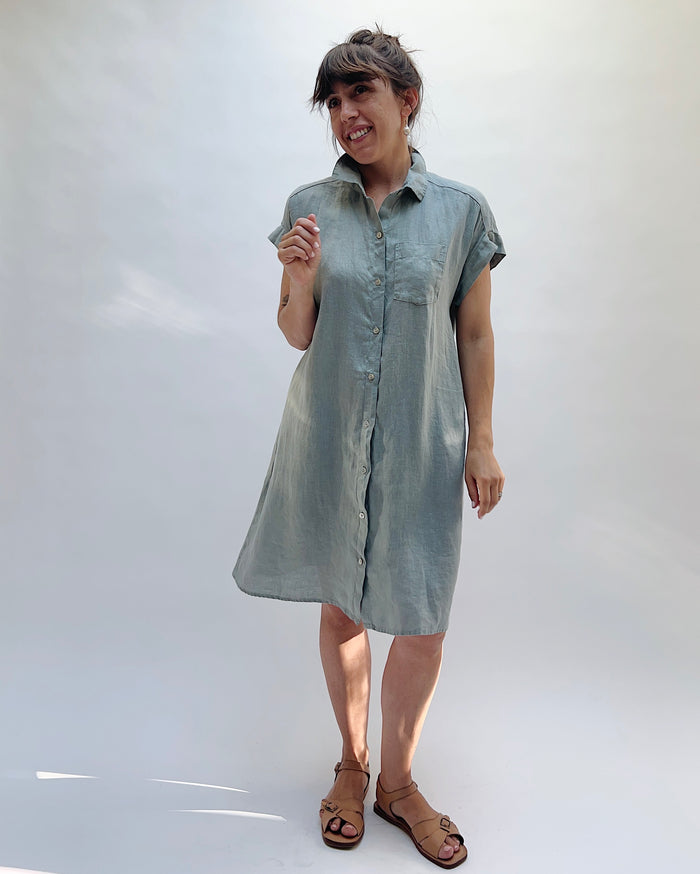Woman wearing a light blue, slightly gray dress against a white background