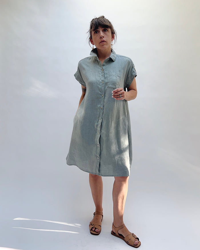 Woman wearing a light blue, slightly gray dress against a white background