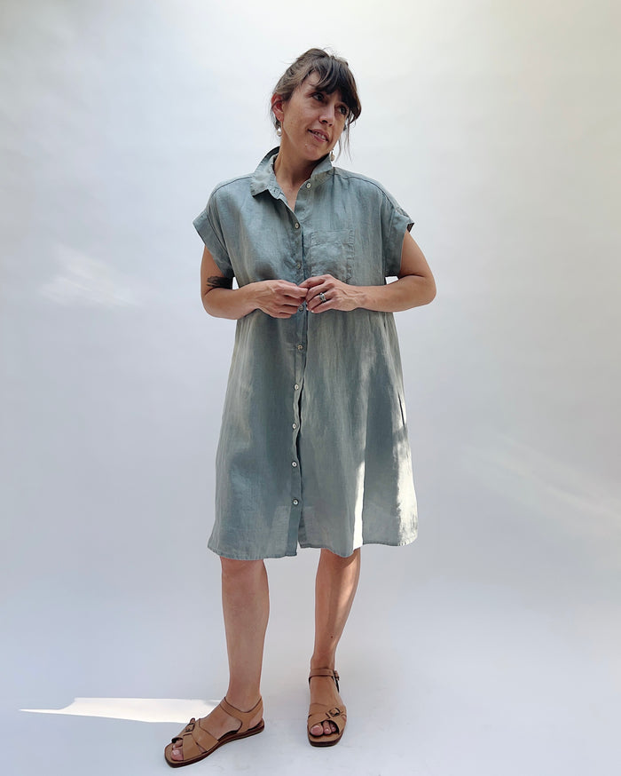 Woman wearing a light blue, slightly gray dress against a white background