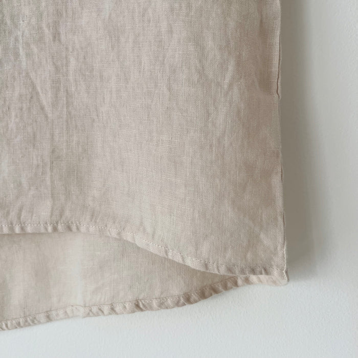 Close-up of the hem of a beige high-low linen tee