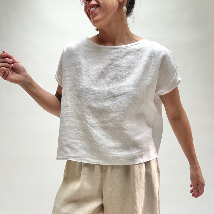 Person wearing a white top and beige pants against a plain background