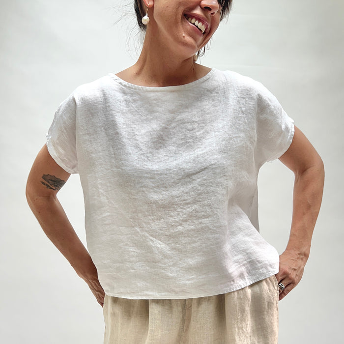 Person wearing a white linen shirt against a plain background
