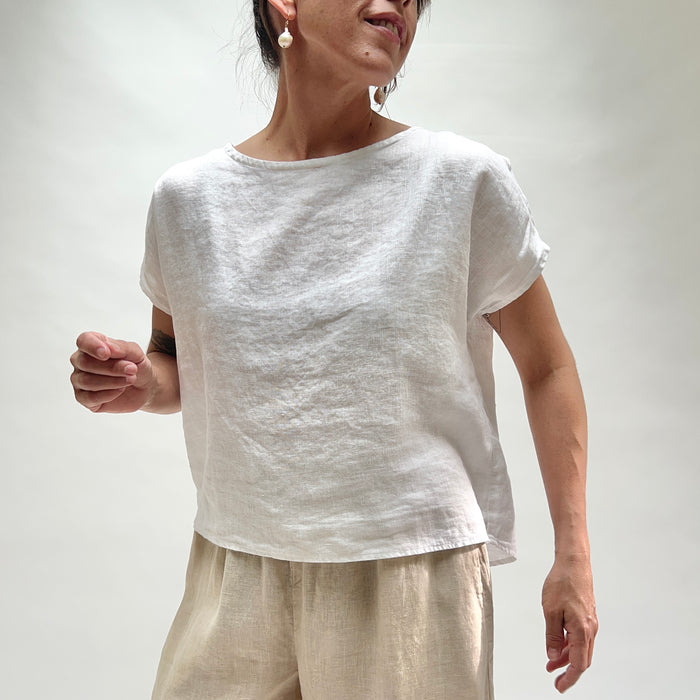 Person wearing a white t-shirt and beige pants against a plain background