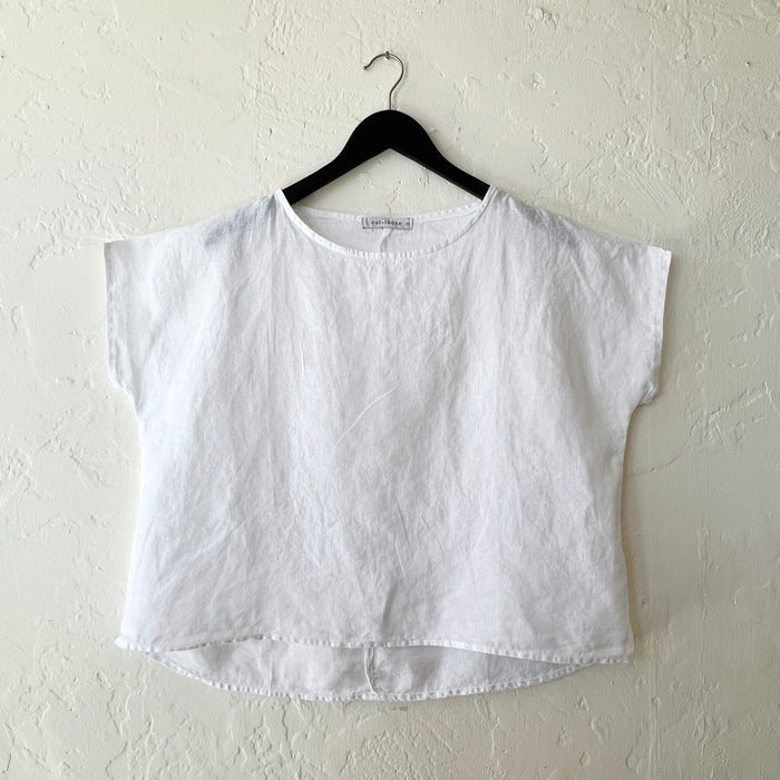 White top on a hanger against a white wall