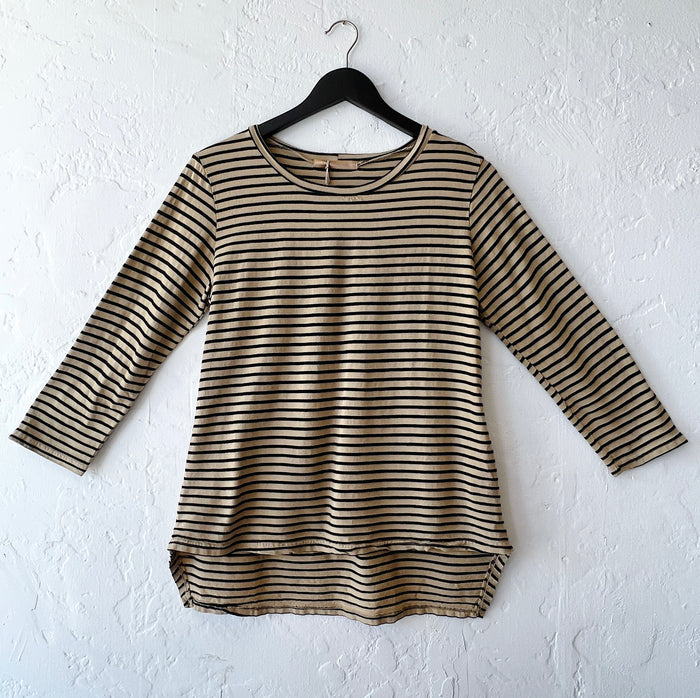 Striped long-sleeve shirt on a hanger against a white wall