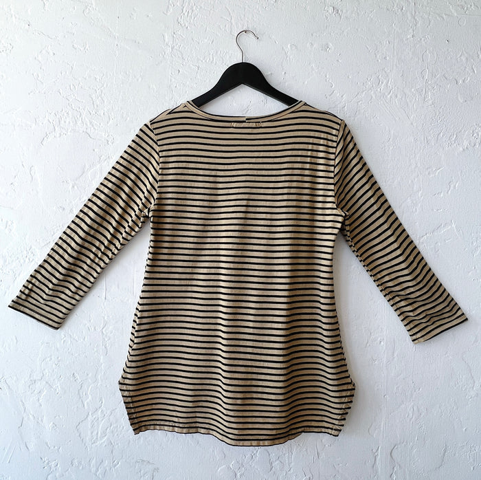 Striped long-sleeve shirt on a hanger against a white wall as viewed from the back