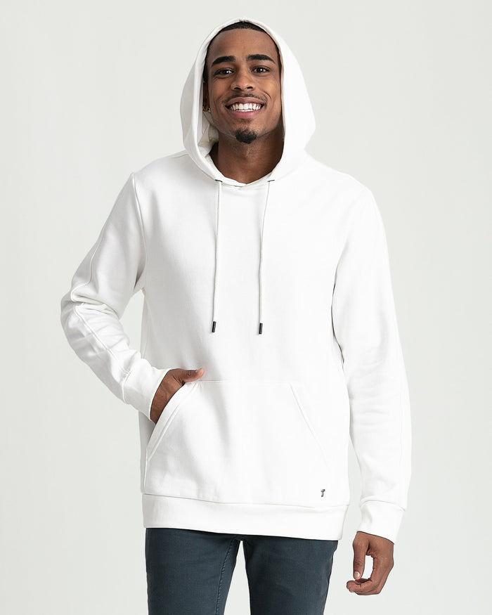 Cream-colored pullover hoodie with drawstring, front pocket, and long sleeves worn with dark jeans.