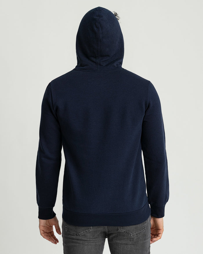 Navy hoodie with drawstring hood, shown from back view on model wearing gray jeans.